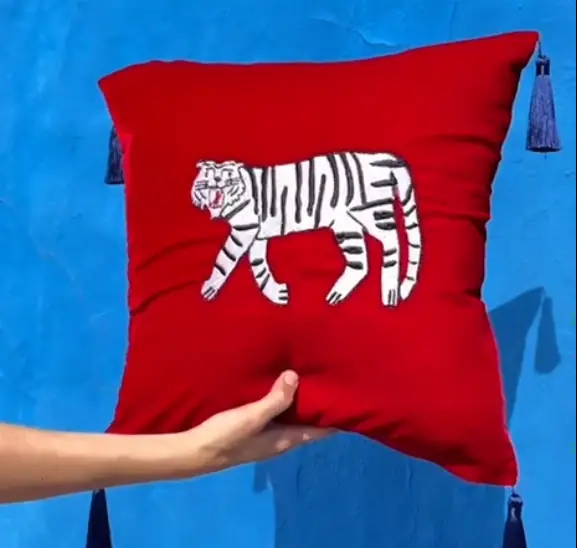 Coussin rouge à pompons bleu marine avec un tigre blanc brodé main