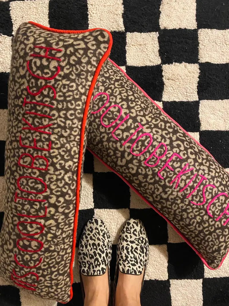 Deux coussins léopard brodés main en rouge et rose sur un tapis damier